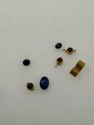 three pairs of gold and blue stone earrings on a white surface