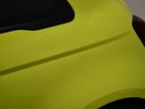 the rear end of a small yellow car with a black roof