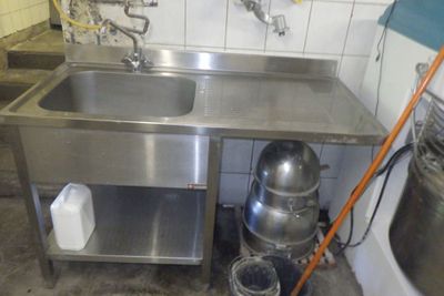un évier en inox dans une cuisine, à côté d'un seau