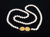 un collier de perles blanches avec un fermoir en or