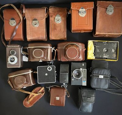 a lot of different types of old cameras on the table