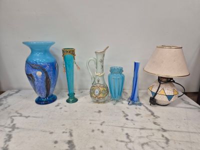 de nombreux vases de différentes couleurs posés sur une table où se trouve une lampe
