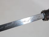 someone is holding a knife with writing on it in their hand