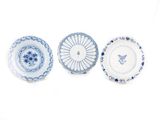 trois assiettes bleues et blanches à motifs sur une surface blanche