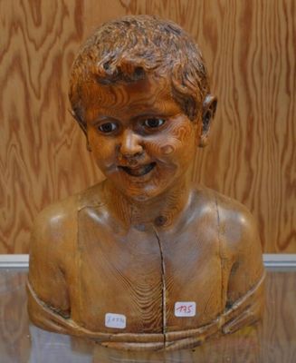 une statue en bois représentant un garçon, exposée dans une vitrine