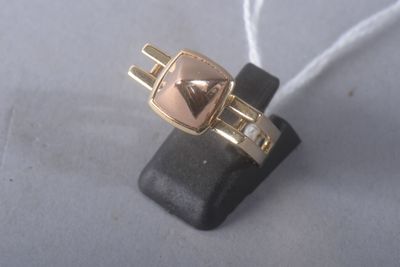 a gold ring with a heart on it sitting on top of a black piece of leather