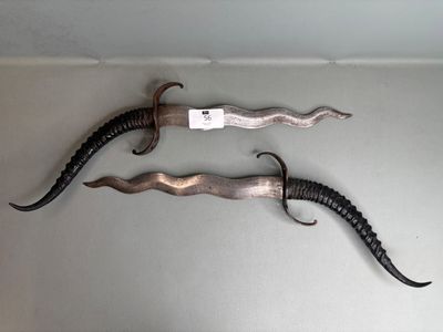 Paire de grands poignards, poignées en corne, lame ondoyante…