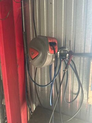 une photo d'un garage avec une porte rouge et un tuyau d'arrosage fixé sur le côté de la porte