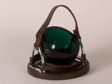 a green bowl sitting on top of a brown holder