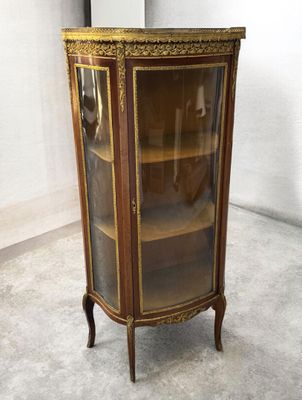 une vitrine ancienne avec une porte vitrée et des moulures dorées