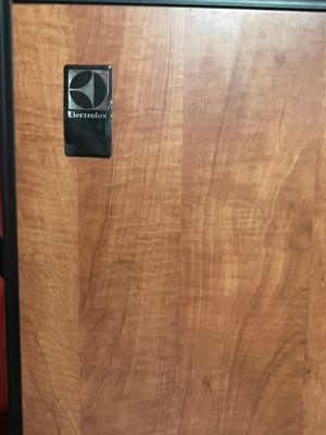 une armoire en bois avec une porte noire sur laquelle est apposée une pancarte
