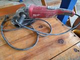 a red and black electric drill on a wooden table