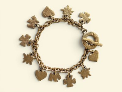 a gold bracelet with charms on it on a white surface