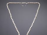 a white pearl necklace with a silver clasp on a gray background