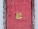 an old silver frame with a small piece of fabric in it