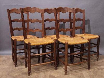four wooden chairs are lined up against a gray wall