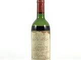 une vieille bouteille de vin posée sur une surface blanche