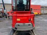 the back end of a red tractor parked in a parking lot