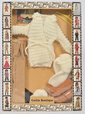 une poupée dans une boîte, avec un pull et des chaussures