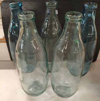 quatre bouteilles en verre vides sont alignées sur une table