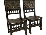 pair of carved wood chairs with floral designs on the backs