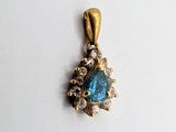 a close up of a blue stone and diamond pendant on a white surface