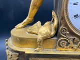 a gold clock with a statue of a man holding a bird
