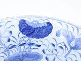 a blue and white plate with a butterfly and flowers on it