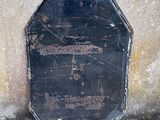 a black sign that is on the ground by a cement wall
