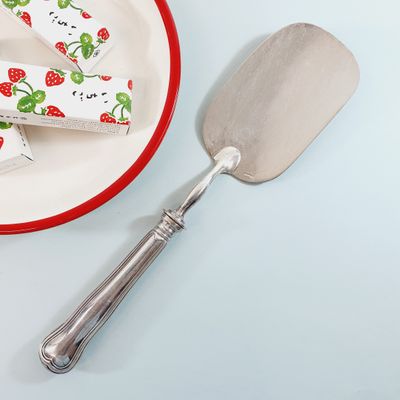 a plate with a piece of cake on it next to a spatula