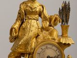 a gold clock with a statue of a woman holding a bird