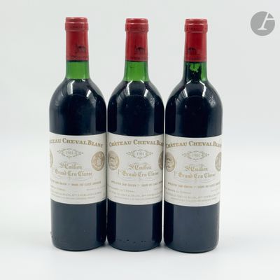 trois bouteilles de vin rouge posées l'une à côté de l'autre sur une surface blanche