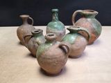several old vases are lined up on a table with a black background