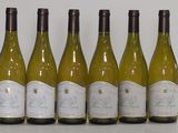 six bottles of white wine lined up in a row on a table