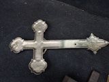 a silver cross on a black surface next to a hammer