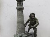 une statue représentant un homme debout à côté d'une horloge, posée sur un socle