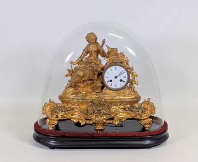 une horloge en or sous un dôme de verre sur une table