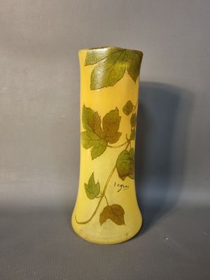 un vase jaune orné de feuilles, posé sur une table