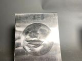 a metal plate with a face on it sitting on a table