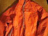 an orange jacket sitting on top of a wooden table next to a laptop computer