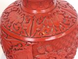 a red vase with a blue lid sitting on a white surface