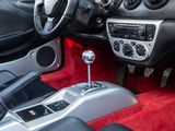the interior of a sports car with red carpeting and black leather seats