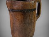 une image représentant une tasse en bois munie d'une anse, sur fond gris