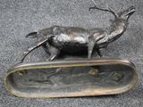 a bronze deer statue sitting on top of a metal tray