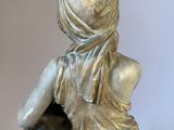 statue of a woman sitting on a rock with a vase in her hand