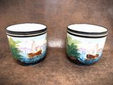 two cups with boats painted on them sitting on a brown surface