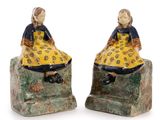 pair of ceramic figurines of a girl and boy sitting on a rock