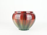 a red and green vase sitting on a white surface