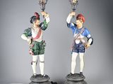 pair of figurines of two men with hats and a sword