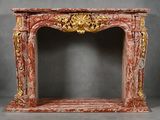 un encadrement de cheminée richement sculpté, surmonté d'un manteau en marbre rouge